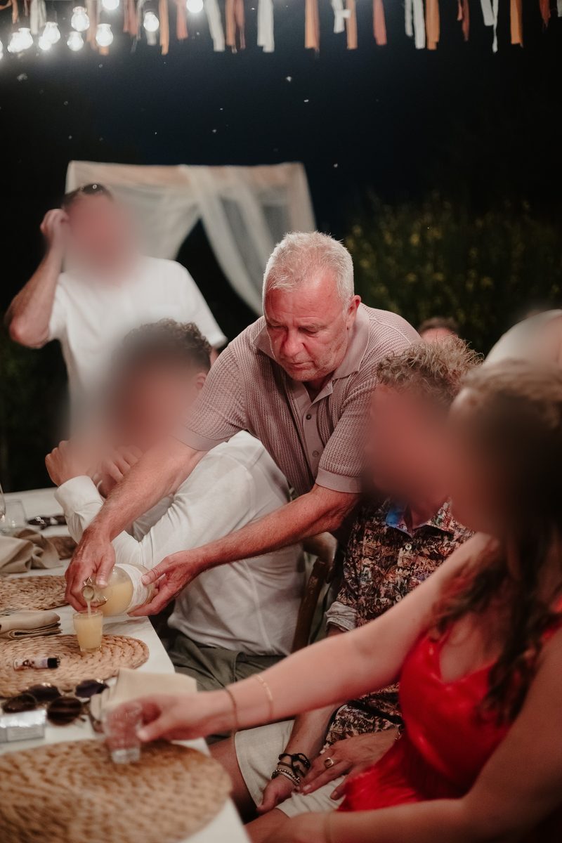 Arie schenkt limoncello in kleine glazen aan een feesttafel buiten in de avond